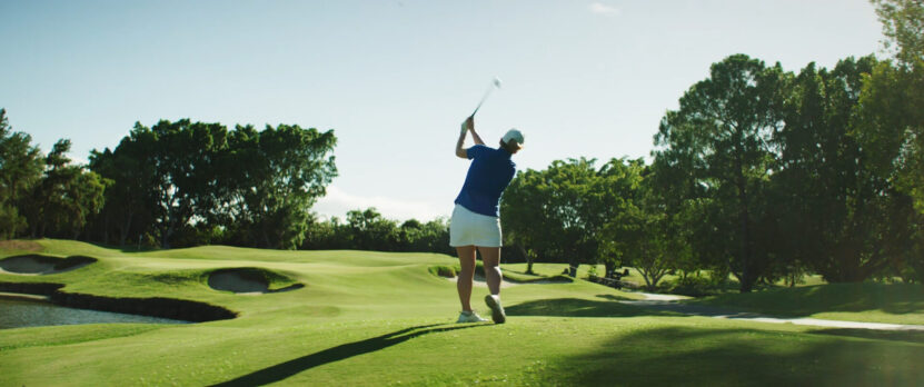 A woman hits the ball in the direction of the wind to increase the distance